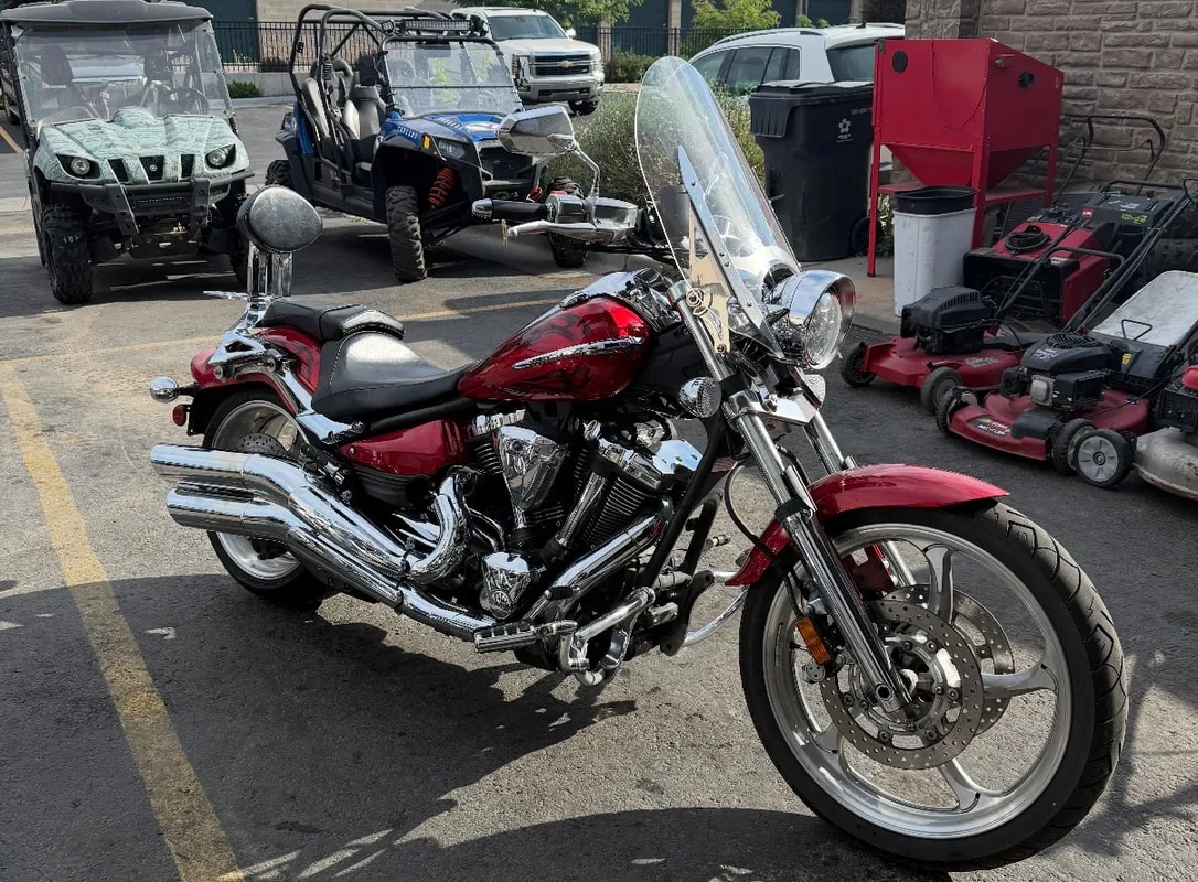 Red cruiser motorcycle with windshield parked outside the shop