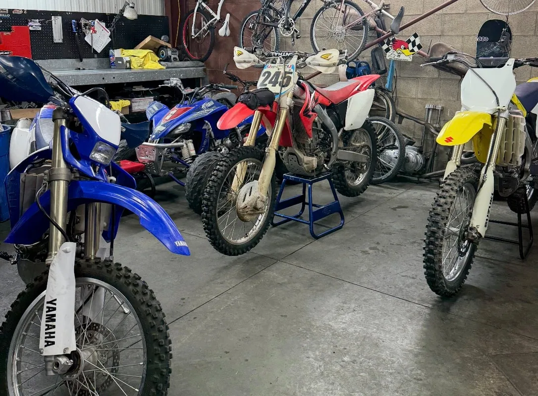 Yamaha, Honda and Suzuki dirt bikes on stands in the service bay