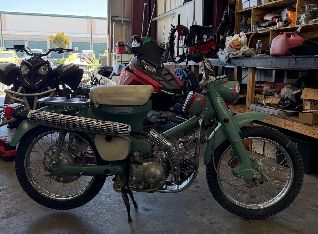 Green Honda trail bike on the bench inside the shop